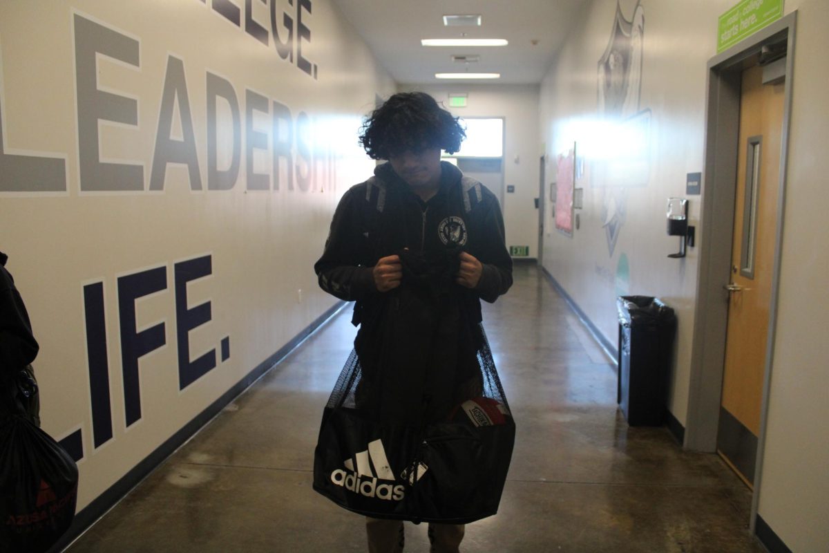 Julio 12th grader stands with the empty volleyball bag 