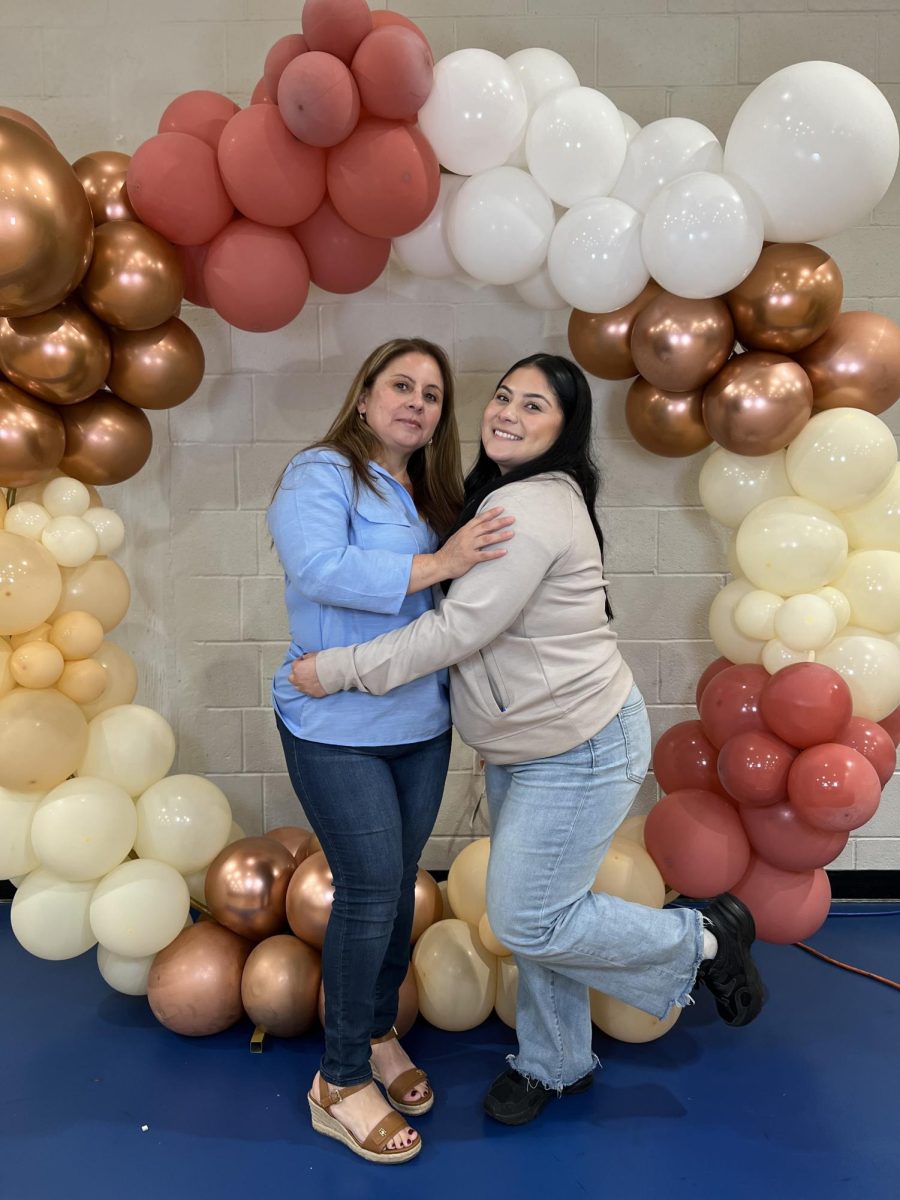 Teacher Aide Ms. Navarro poses with her mom in front of the backdrop. 
